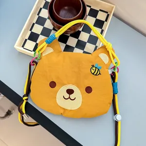 Detailed view of the cute cartoon bear face embroidery on a yellow crossbody phone bag