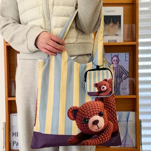 Vue détaillée d'un sac cabas avec imprimé ours au crochet et rayures jaunes et bleues.