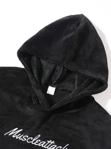 Close-up view of a black plush hoodie featuring white embroidered Muscleattack lettering