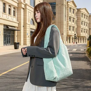 Stylish mint green textured tote bag carried by a model in an urban street setting