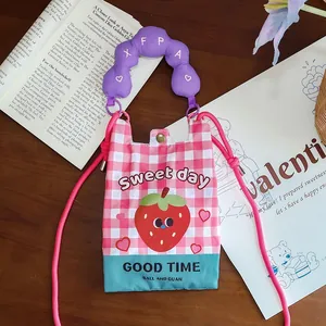 Detail of a pink gingham crossbody phone bag with strawberry graphic and purple handle