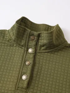 Detalle de sudadera acolchada verde con cuello alto y botones metálicos