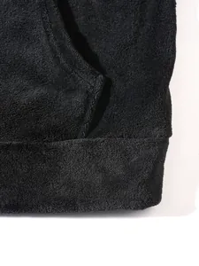 Close-up macro detail of the soft black plush texture on a warm men's loungewear hoodie