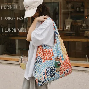 Close-up of a colorful patterned tote bag with bear embroidery carried by a model.