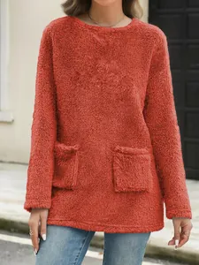 Detail view of rust red plush sweatshirt featuring soft fleece texture and front pockets.