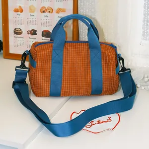 Dettaglio della borsa bowling a scacchi arancione con una vivace tracolla blu regolabile.