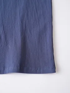 Close-up detail of the hem of a navy blue linen shirt showing the fine stitching workmanship