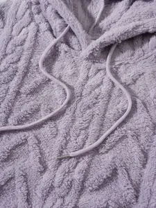 Κοντινό πλάνο της μαλακής μοβ υφής fleece και της λεπτομέρειας με κορδόνι σε γυναικείο φούτερ.