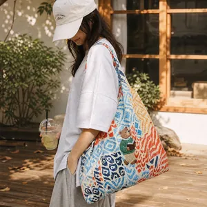 Detail view of colorful painted tote bag with bear embroidery in outdoor setting