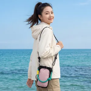 Asian woman wearing a stylish pink and black crossbody phone bag by the seaside