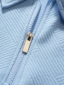 Makro-Detailansicht des hochwertigen Reißverschlusses und Strukturstoffs am hellblauen Polo