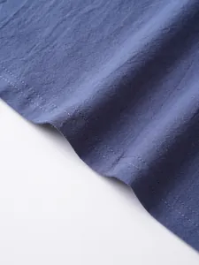 Detailed close-up of blue breathable linen fabric texture and hem stitching quality