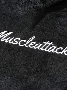 Detailed close-up showing white cursive embroidery on black fuzzy men's fleece loungewear
