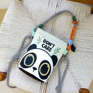 Detailed view of a canvas crossbody bucket bag featuring a cute panda print and text