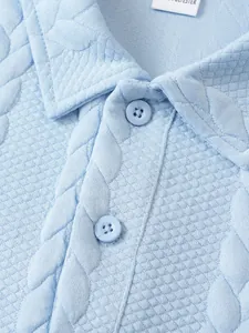 Detailopname van een lichtblauwe polokraag met getextureerd jacquard breisel.