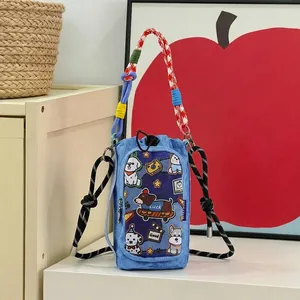 Detail view of various cute cartoon dog patches on light blue denim phone pouch bag