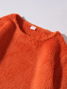 Close-up view of fuzzy orange polyester sweatshirt with visible size and care tag