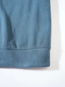 Detailansicht der blauen Fleece-Stoffstruktur und Saumnaht an einem Herren-Sweatshirt.