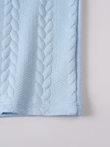 Detailed macro view of the light blue cable-knit jacquard fabric of the men's polo shirt