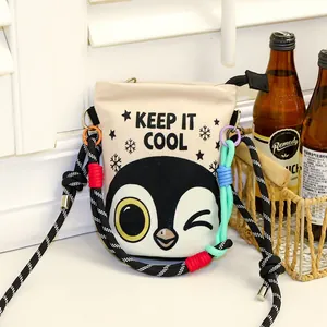 Detail view of a beige canvas bucket bag with a cute penguin print and rope strap.