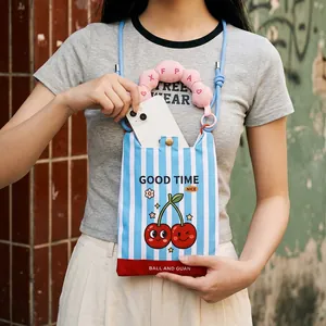 Detail showing a smartphone fitting into a striped crossbody bag with cherry print