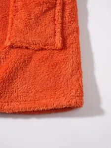 Close-up of orange plush fleece sweatshirt detail showing hem and pocket texture.