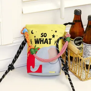 Detail view of a yellow cartoon elephant print bucket bag featuring colorful braided rope straps