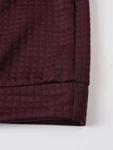 Primer plano detallado de sudadera burdeos que muestra la textura de rejilla y la costura.