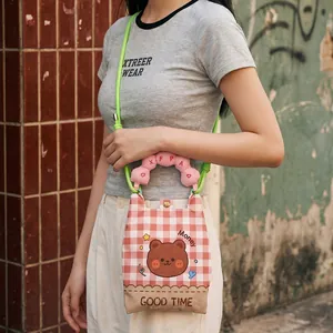 Lifestyle detail view of a cute cartoon bear crossbody bag worn by a young woman