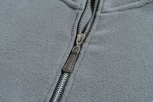 Detalle de una cremallera metálica plateada en una chaqueta de forro polar gris.