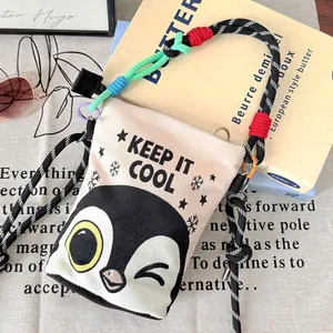 Close-up detail of the playful cartoon penguin print on a canvas crossbody bucket bag