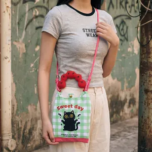 Detailed view of cute cartoon cat crossbody phone bag with green checkered canvas pattern