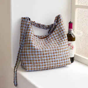 Elegante borsa a tracolla a quadretti ricamata con fiori su un davanzale bianco