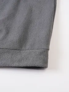 Detailaufnahme der weichen grauen Polarfleece-Struktur am Saum eines Herrenpullis