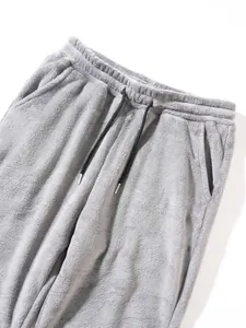 Close-up of grey plush fleece trousers with drawstring waist and pocket detail.