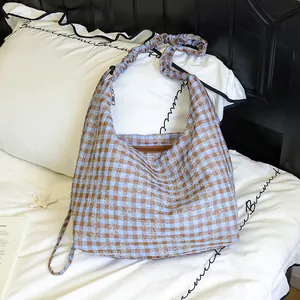 Dettaglio di una borsa a tracolla coreana a quadretti con fiori e tracolla arricciata