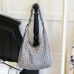 Dettaglio della borsa hobo a scacchi blu e marroni con ricamo floreale bianco puro