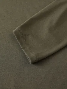 Gros plan du poignet d'un polo vert olive à manches longues montrant les coutures et le tissu