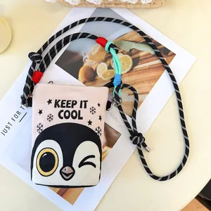 Detailed view of a cartoon penguin print crossbody bucket bag with colorful rope strap.