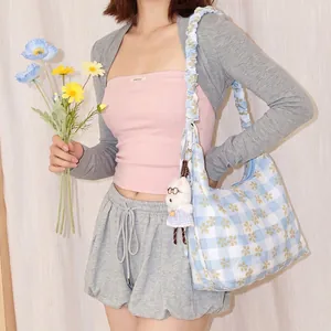 Dettaglio di una borsa a tracolla vichy blu floreale con ciondolo a coniglio.