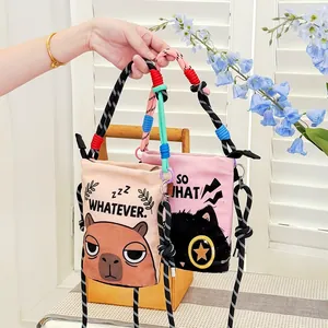 Detail view of two cartoon printed crossbody bags featuring capybara and cat designs