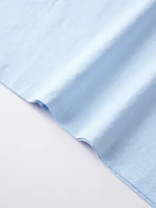 Macro view of light blue breathable linen fabric showing high-quality hem stitching detail