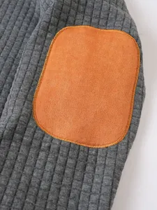 Vista detallada de la tela acolchada gris con patrón de cuadros y parche naranja