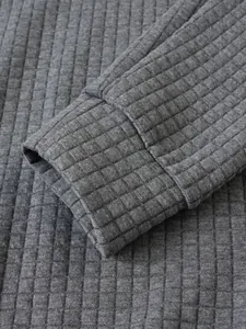 Detalle del puño de una sudadera gris con textura de rejilla acolchada para hombre