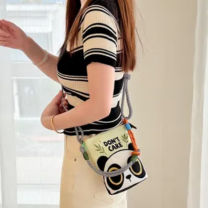 Detail shot of a cartoon panda crossbody bucket bag with woven straps on a model