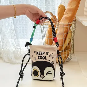 Handheld view of cartoon penguin canvas bucket bag with colorful rope straps