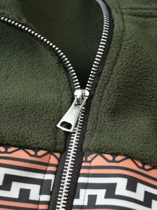 Nahaufnahme des silbernen Reißverschlusses am grünen Fleece-Sweatshirt mit geometrischem Muster