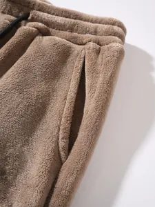 Detail view of brown fleece jogger pants focusing on elastic waistband and soft pocket texture.