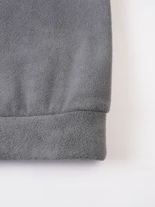 Makroansicht der weichen grauen Fleece-Textur und Nähte eines warmen Herren-Sweatshirts.