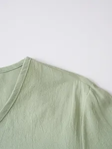 Close-up of light green breathable linen fabric texture on men's V-neck casual top